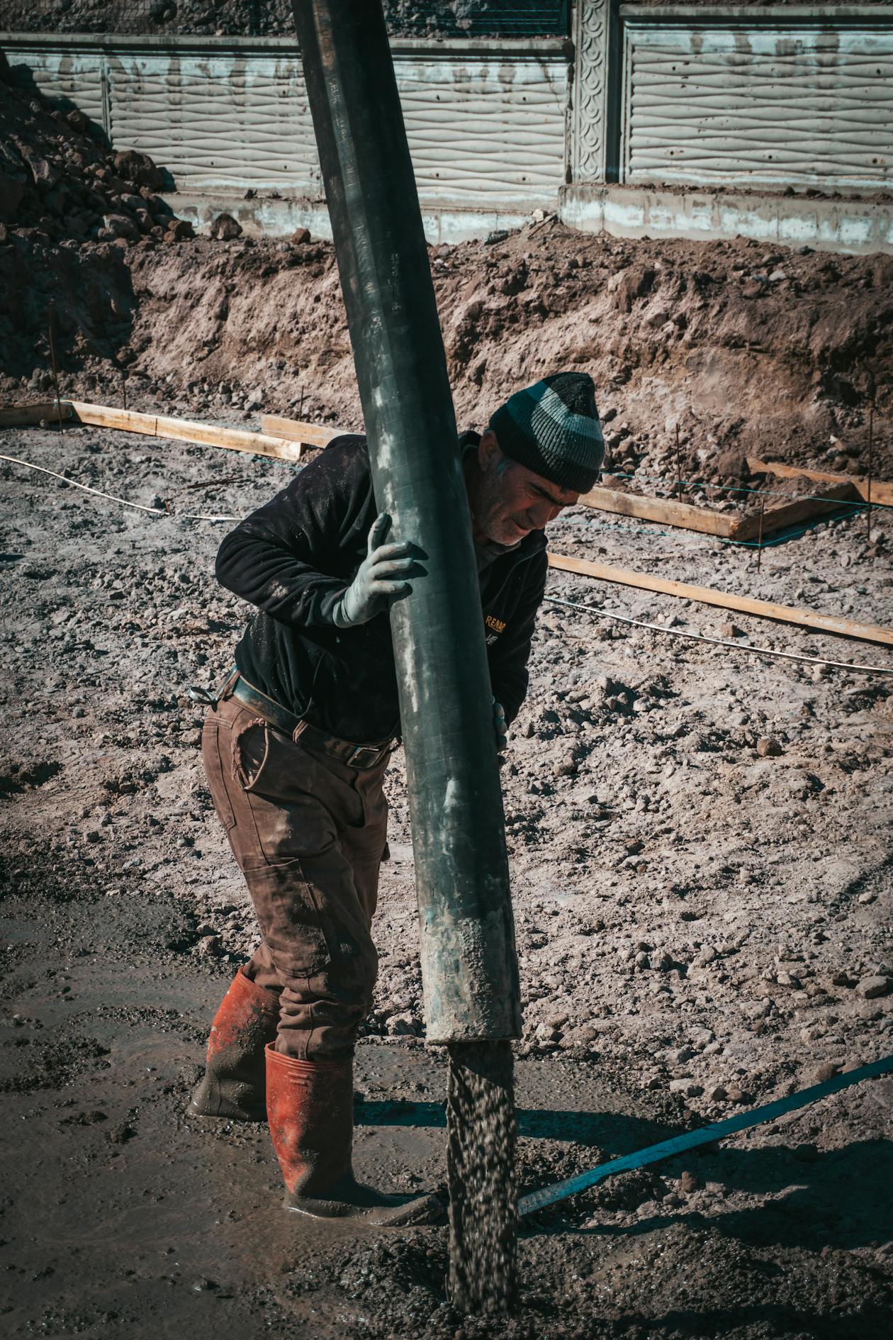 Construction worker pouring concrete into footings and formwork on a job site