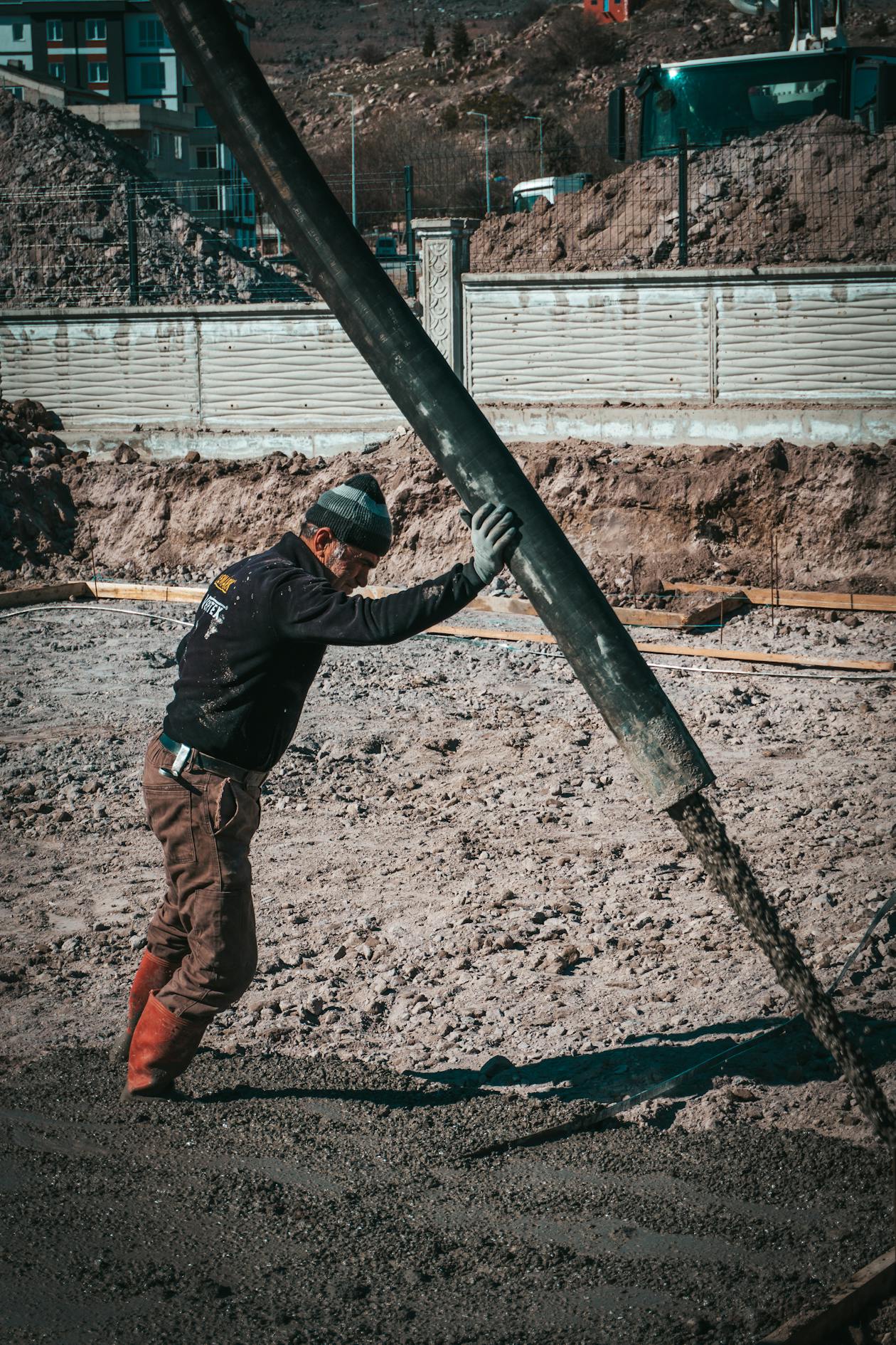 Construction worker pouring concrete with a pump hose at a residential job site